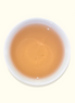 White ceramic cup filled with a light brown liquid on a white background