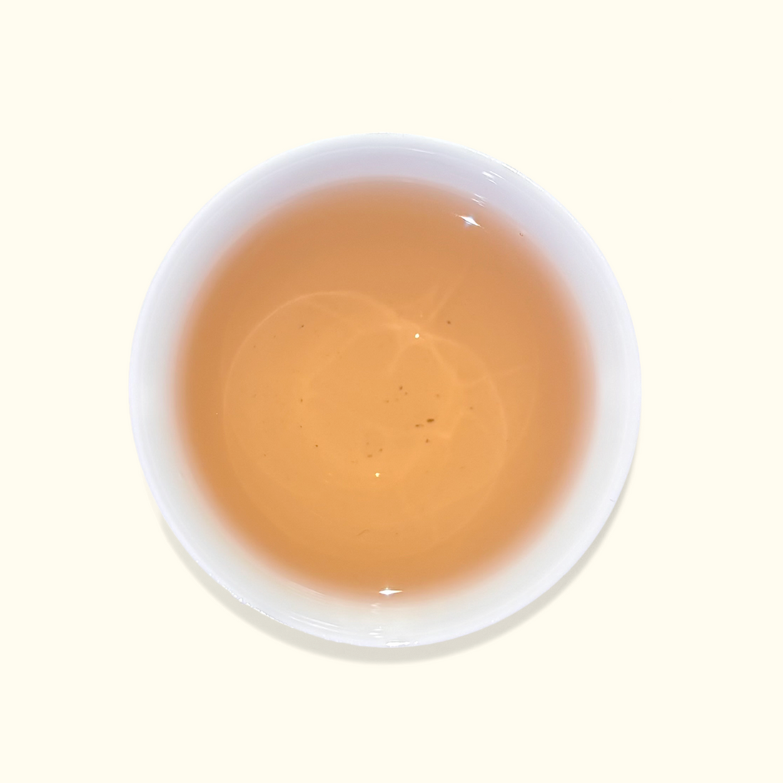 White ceramic cup filled with a light brown liquid on a white background