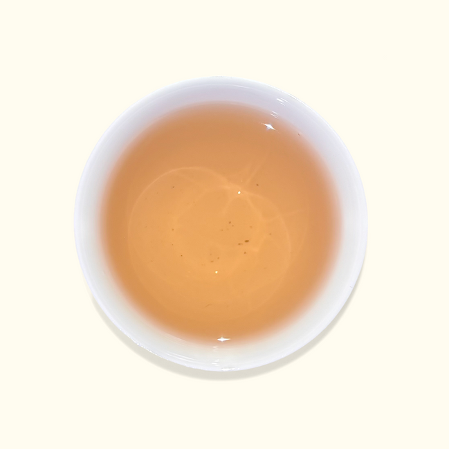 White ceramic cup filled with a light brown liquid on a white background