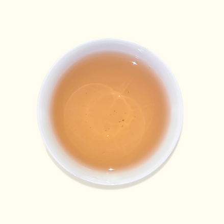 White ceramic cup filled with a light brown liquid on a white background